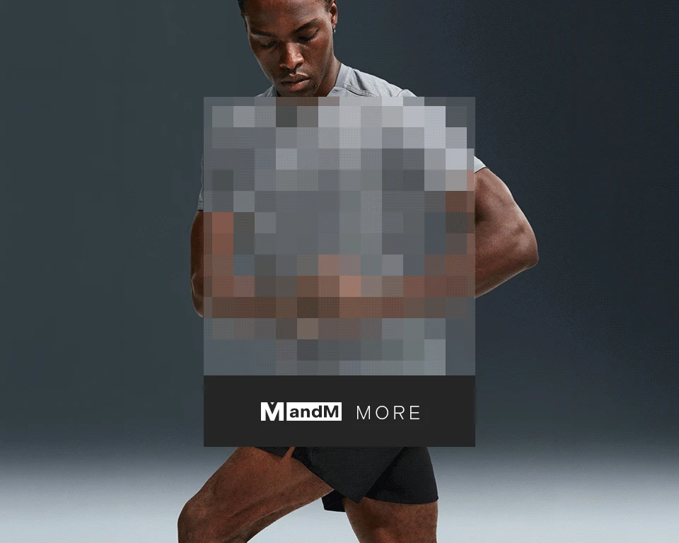 A dark-skinned man in a light grey athletic t-shirt and black shorts, posing in fitness apparel against a dark background. Women's periwinkle athletic zip-up top with thumbholes, paired with dark performance pants.
